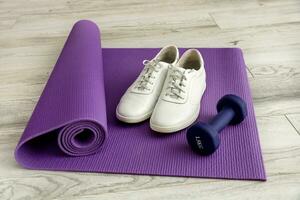 white sneakers with dumbbells on a lilac gymnastic mat, sports training photo