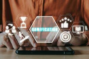 Gamification concept, Person hand using smart phone on desk with gamification icon on virtual screen. photo