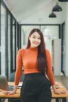 Portrait of young smiling woman looking at camera with crossed arms. Happy girl standing in creative office. Successful businesswoman standing in office with copy space. photo