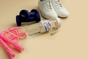 sneakers, jump rope, water bottle, dumbbells on a light background with copy space photo