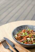 A bowl of udon noodles, veal and fried vegetables angle view on wooden table photo