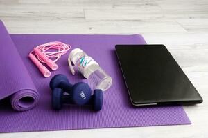 laptop on gymnastic mat with sports equipment, online sports photo