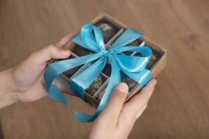 Gift box with chocolate craft candies in boys hands. Sweet gift box photo