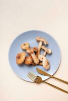 Mushrooms on a plate with cutlery flat lay, top view on beige background photo