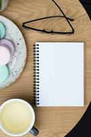 Blank note with cup of tea and macarons on cafe table background flat lay photo