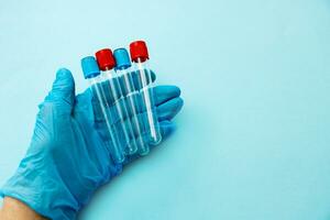 empty test tubes in the hand of a medic in a glove on a blue background photo