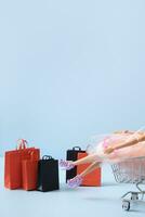 Doll in supermarket basket with shopping bag. Sale concept. Copy space. photo