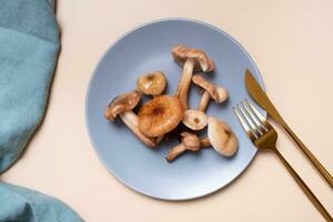 Mushrooms on a plate with cutlery flat lay, top view on beige background photo