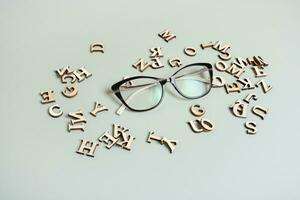 Eyeglasses on pastel green background with wooden letters. Vision test,optical store concept photo