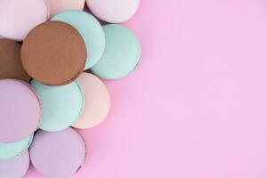 Different pastel colors pastry macarons on a pink background with copy space photo