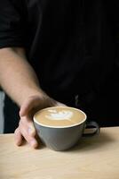 Barista hand serving coffee latte with art photo