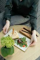 Burger with meat on a wooden table in female hands photo