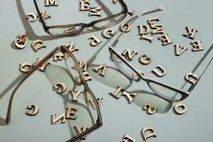 Eyeglasses on pastel green background with wooden letters. Vision test,optical store concept photo