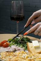 Female hands with cutlery eating omelette with turkey and vegetables. A glass of wine on the background photo