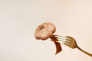 Honey fungi mashroom on a fork on a beige background photo
