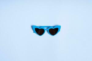 Children's sunglasses in the shape of a heart on a blue background, top view photo