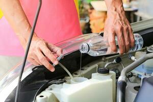 Llene el líquido de agua del parabrisas de un automóvil. foto
