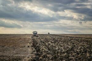 Day view of tractors plowing the soil in a mountain hill. Horizontal view photo