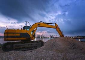 tractor excavador durante movimiento de tierras trabajos en construcción sitio a puesta de sol foto