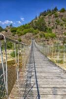 de madera cuerda suspensión puente para caminar cruce río en el montaña foto