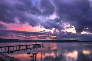 Mood and tranquility at a lake coast with the boat at a wooden pier photo