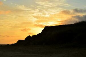 Sun Setting Over Volcanic Rocks on the Coast photo