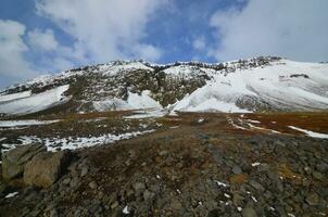 rocoso escabroso montaña con nieve cubrir en el verano foto