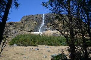 View Up to a Waterfall Over a Large Rock Precipice photo