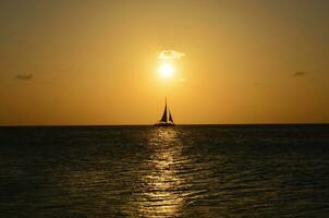 Sailboat Silhouetted on the Ocean Waters in Aruba photo