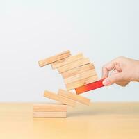 woman hand pulling wood domino blocks on table. Crisis, fall Business, Risk management, Economic recession, Strategy and solutions concept photo