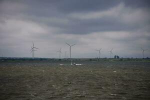verano paisaje con un nublado cielo y un viento granja en el horizonte a disco bahía en Polonia foto