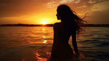 joven mujer s silueta en contra un puesta de sol terminado el mar foto