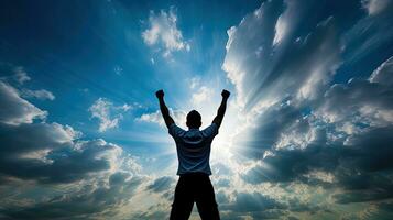 Achievement man silhouetted against blue sky and white clouds photo