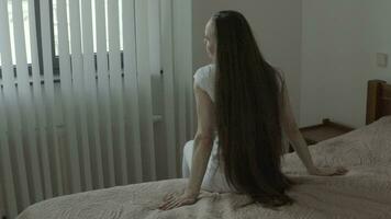 uma mulher sentado em uma cama com dela mãos estendido video