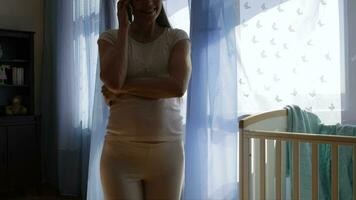 un embarazada mujer en pie en frente de un ventana con un taza de café video