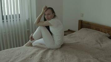 un mujer sentado en un cama con su manos extendido video
