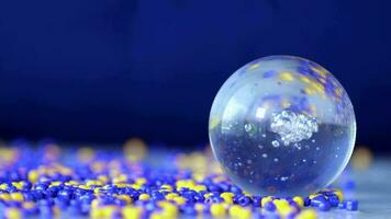 a glass ball with blue and yellow beads on it video