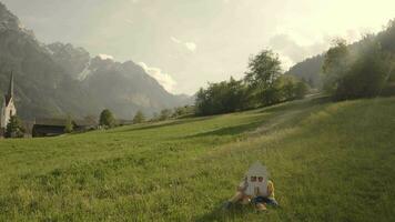 un' ragazza e un' ragazzo Tenere un' Casa ritagliare seduta nel il erba su un' collina video