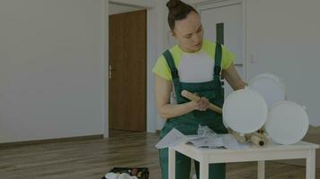 a woman in overalls is working on a table video