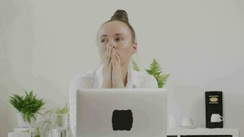 une fatigué femme séance à une bureau en utilisant une portable video