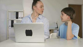 un mujer y un chico son mirando a un ordenador portátil video