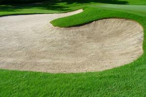 Golf Course Sand Pit Bunkers, green grass surrounding the beautiful sand holes is one of the most challenging obstacles for golfers and adds to the beauty of the golf course. photo