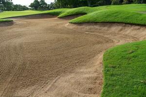 Golf Course Sand Pit Bunkers, green grass surrounding the beautiful sand holes is one of the most challenging obstacles for golfers and adds to the beauty of the golf course. photo