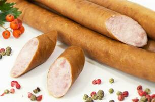 Tasty sausages and vegetables isolated over solid background photo