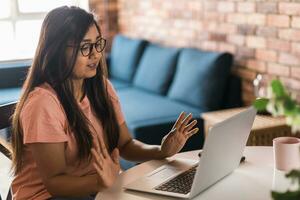 Latino or indian woman use their laptop in living room to make video calls. Video call and online chat with family photo