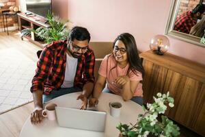 Latino or indian man and woman couple use their laptop in the living room to make video calls. Video call and online chat with family photo