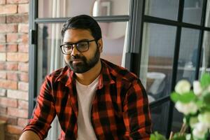 Head shot portrait smart confident smiling millennial indian man. Handsome hindu student guy freelancer at home photo