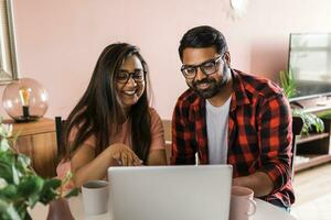 Latino or indian man and woman couple use their laptop in the living room to make video calls. Video call and online chat with family photo