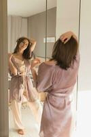 Happy morning. Attractive young woman looking in mirror at her apartment photo