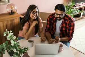 Latino or indian man and woman couple use their laptop in the living room to make video calls. Video call and online chat with family photo